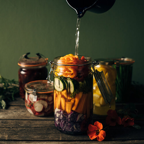 Verduras para fermentar: zanahoria, calabacín y lombarda en un tarro cubiertos con salmuera